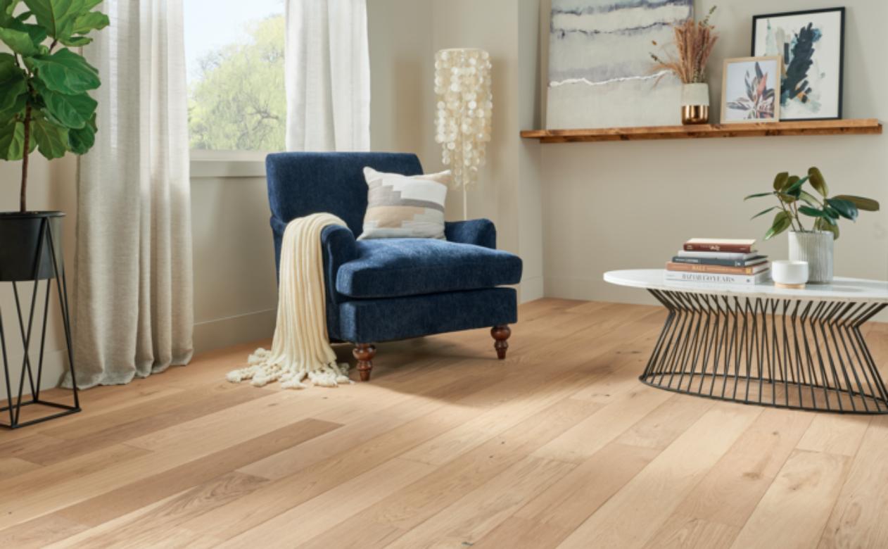 warm toned hardwood flooring in living room with blue antique chair and metal coffee table