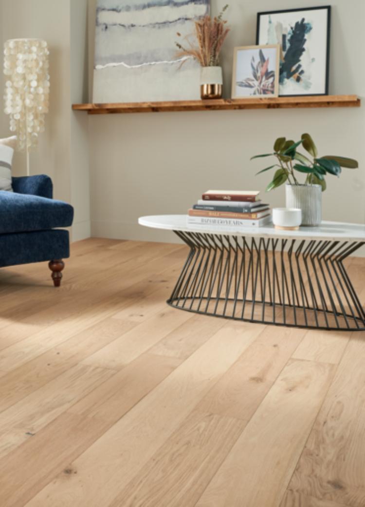 warm toned hardwood flooring in living room with blue antique chair and metal coffee table